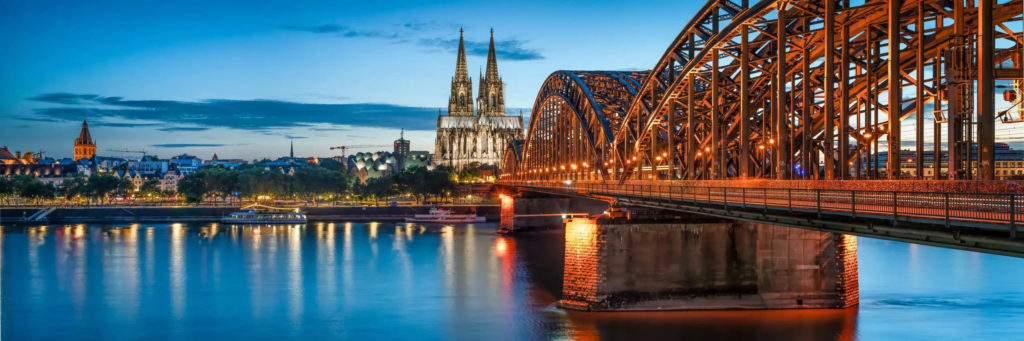 Panoramic view of Cologne's skyline with a bridge crossing the Rhine River. Fly private to Cologne and enjoy the city's historic architecture and modern landmarks from above