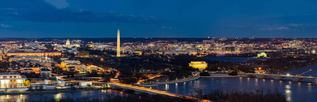 Panoramic view of Washington DC skyline at night, with the illuminated Washington Monument at the center